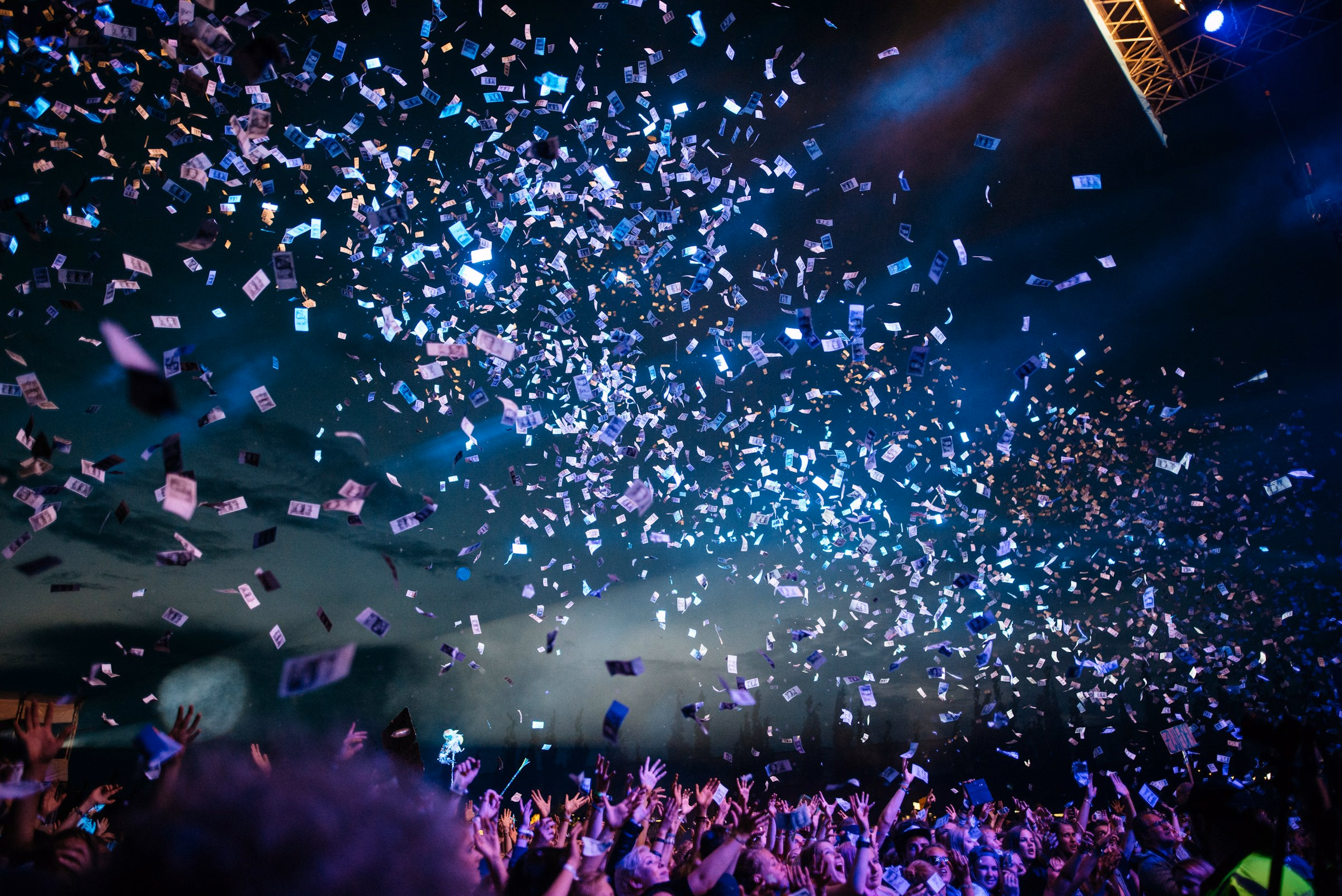 Abstract event atmosphere with confetti and stage light; editorial image, not WEAVE client work
