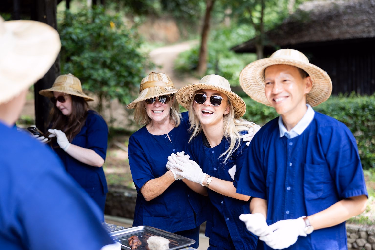 Guests in indigo clothing and woven hats smiling during a shared activity