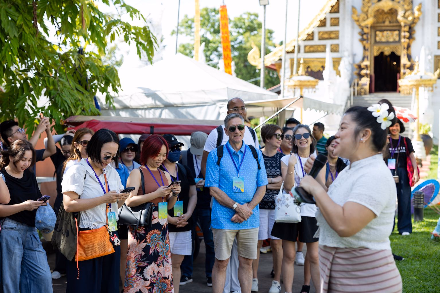 A Thai host speaking with international guests beside a temple in Chiang Mai
