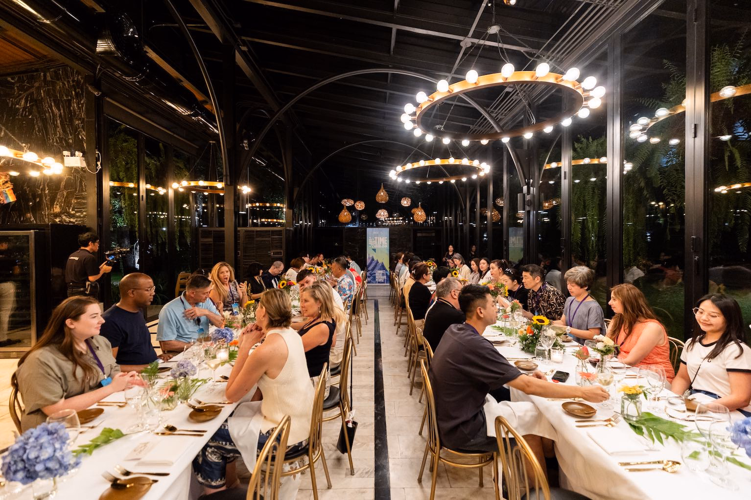 Guests sharing an elegant long-table dinner beneath warm evening lights