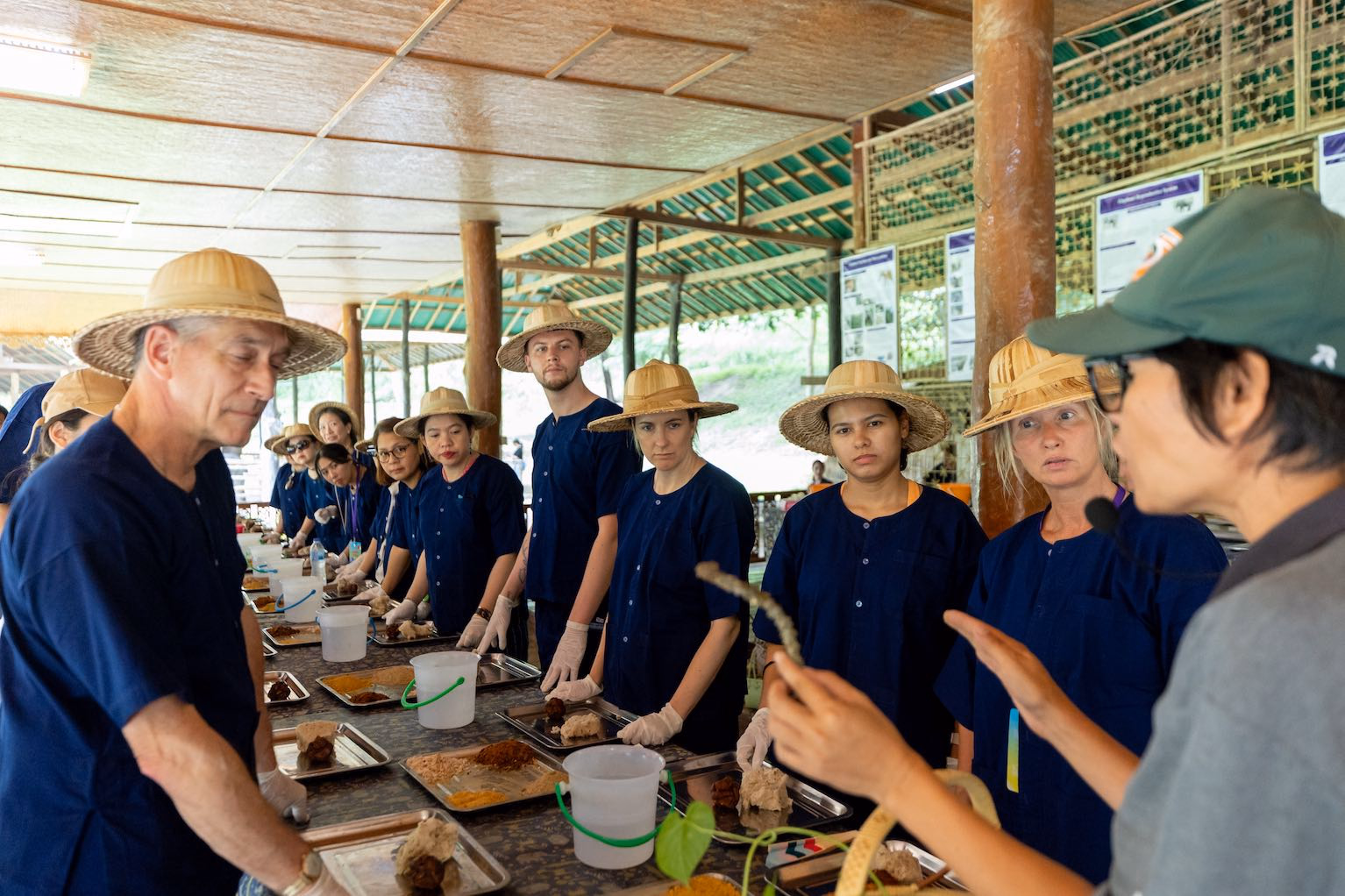 Guests in indigo clothing taking part in a hands-on activity led by a Thai host