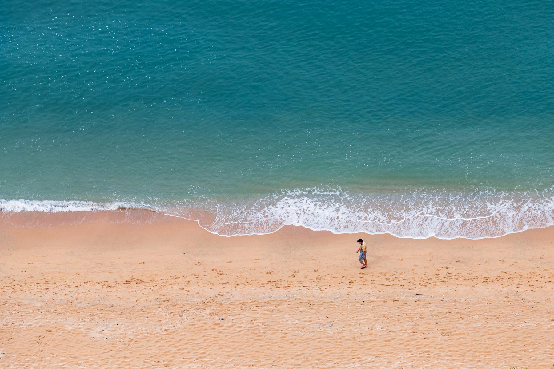 Aerial view of turquoise water meeting a sandy beach in Pattaya